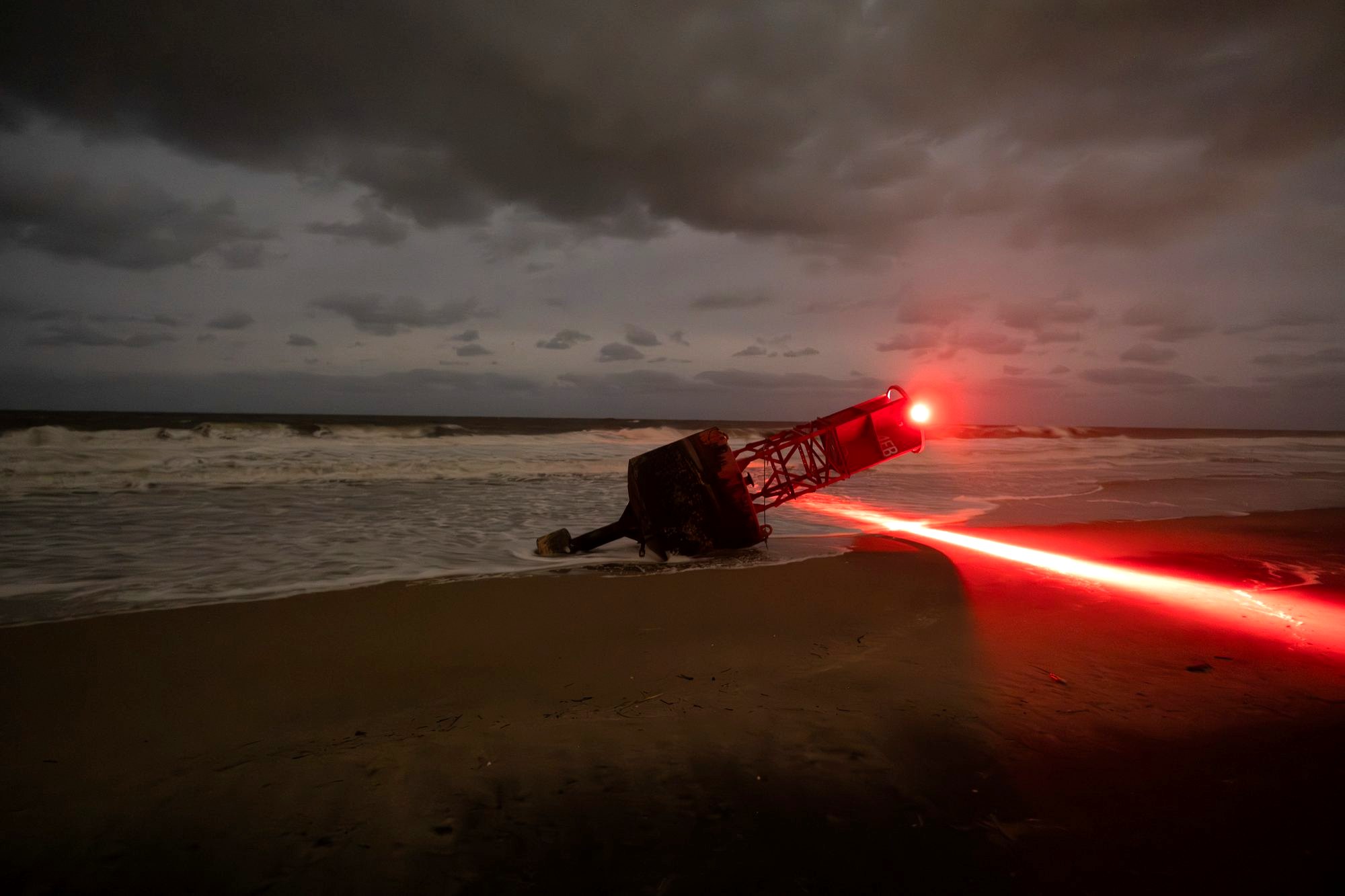 Bethany Beach buoy washed ashore after a storm, red light streaking across the sand